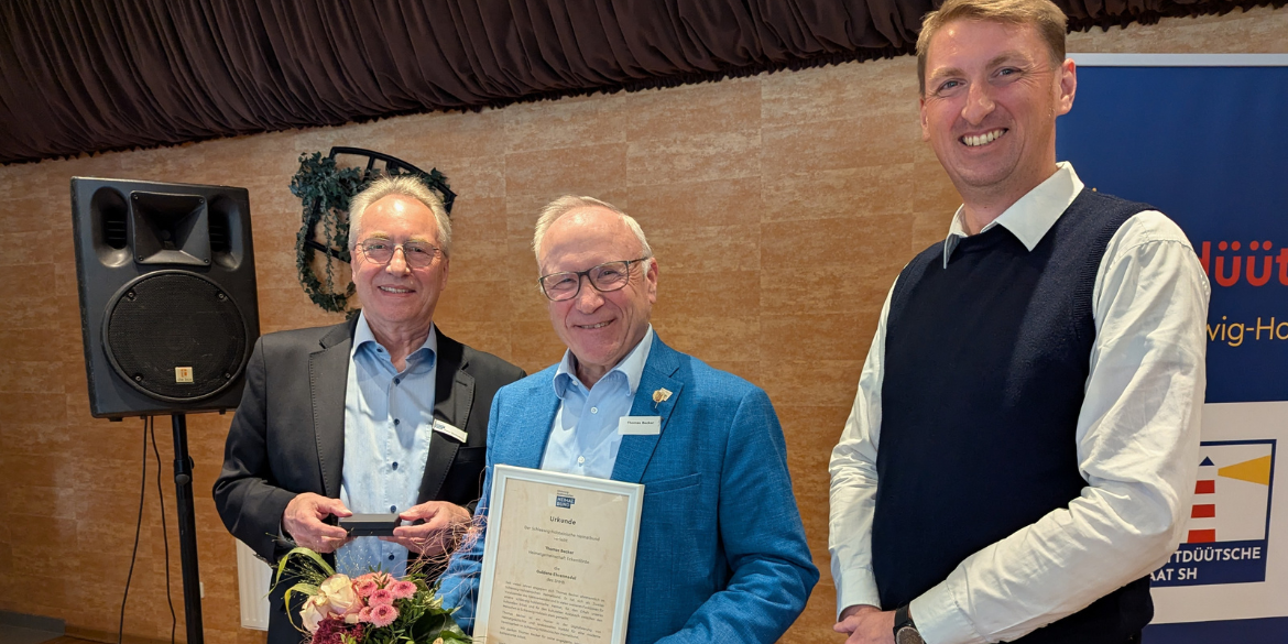 Drei Personen, eine davon hält eine Urkunde