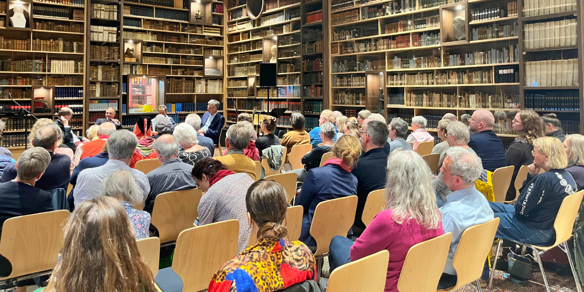 Publikum und Podiumsteilnehmende in Bibliothek