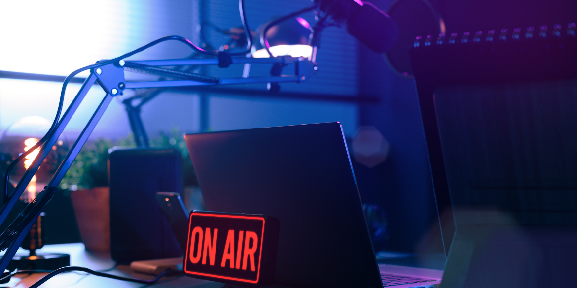 Schreibtisch mit Laptop, Mikrofon und Leuchtschild "ON AIR"