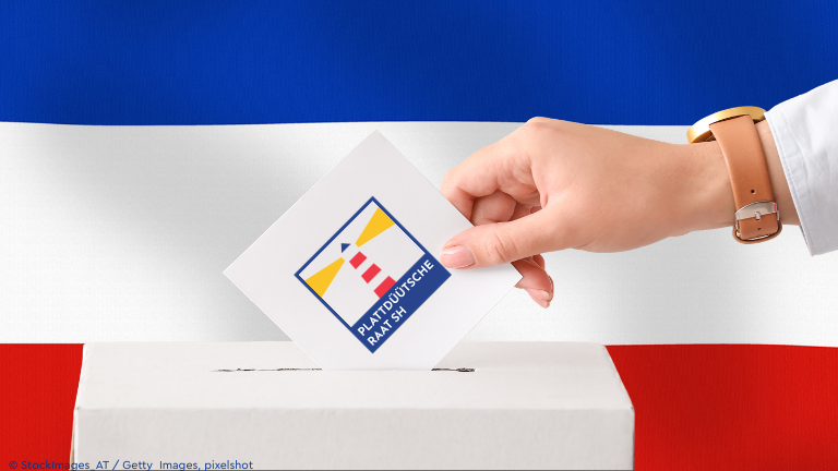 Wahlurne, im Hintergund SH Flagge, Wahlzettel mit Logo des Plattdeutschen Rates SH
