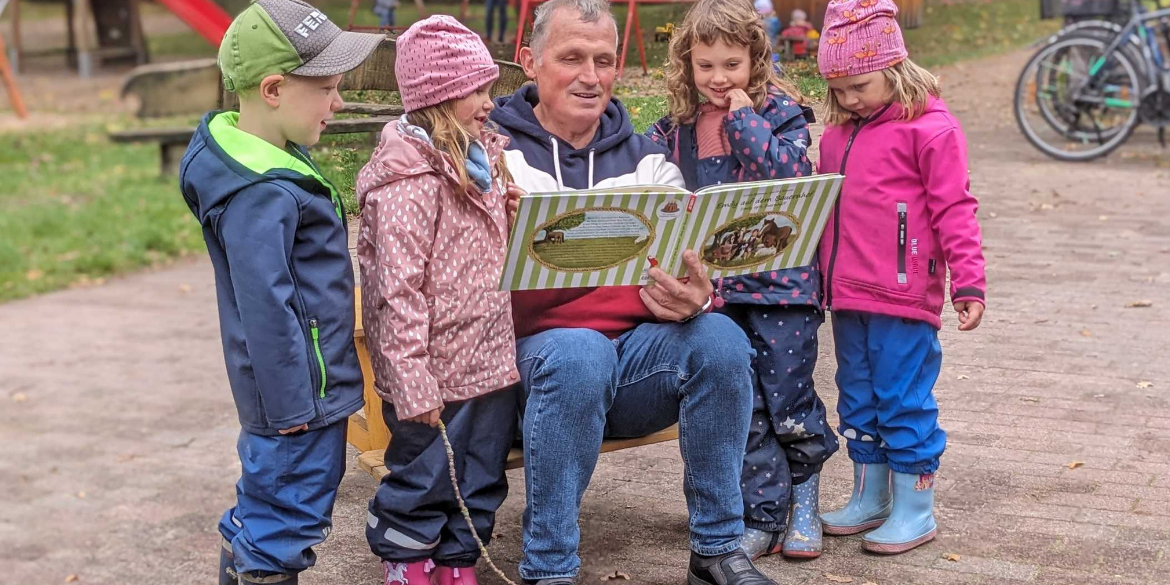 Bokels Bürgermeister Ralf Horstmann liest Kindern aus einem plattdeutschen Buch vor